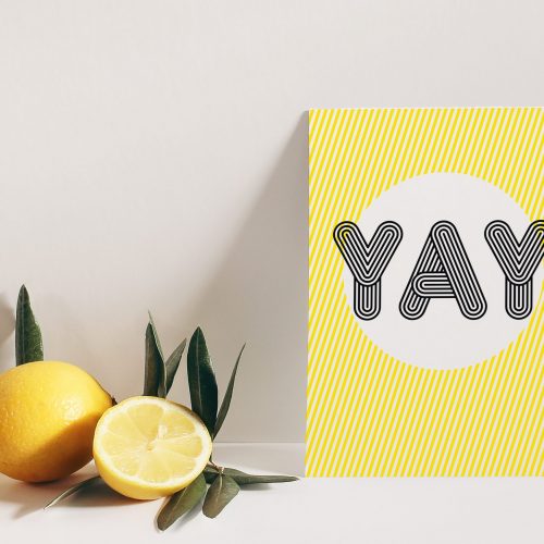 Summer stationery still life scene. Cut lemon fruit and olive tree branch on white table background in sunlight. Blank vertical greeting card mockup leaning against beige wall, branding concept.